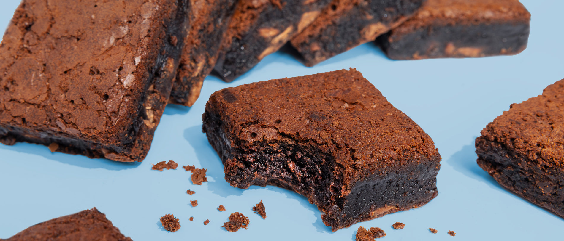Image of bitten Triple Chocolate Brownies on blue background