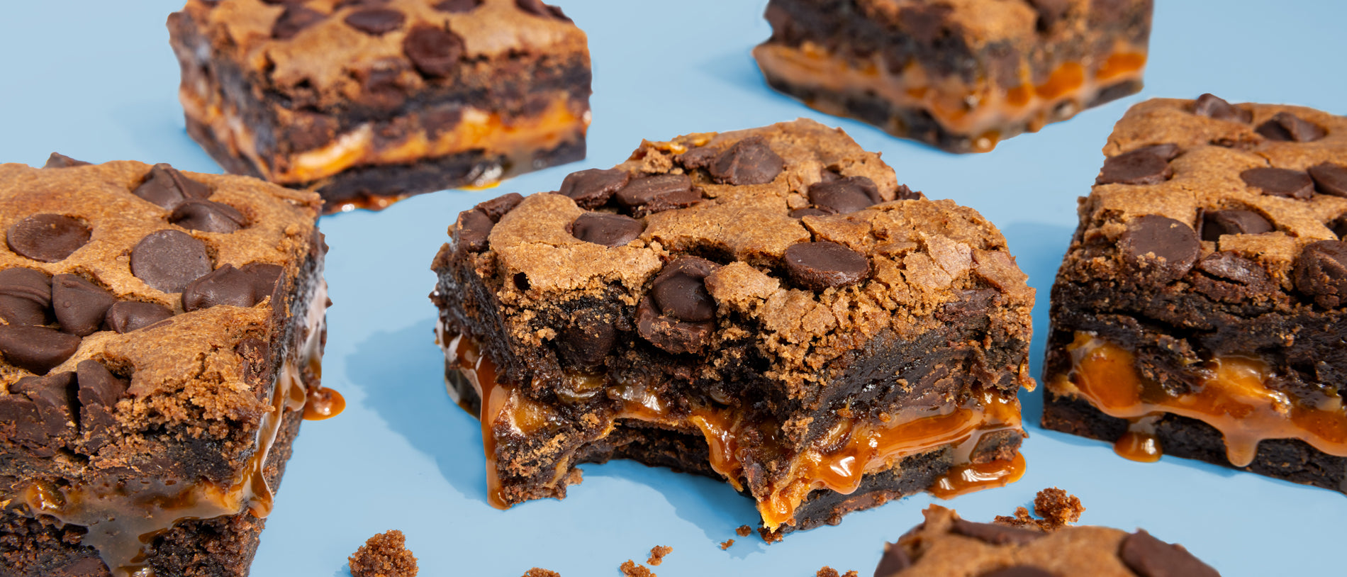 Image of bitten Triple Chocolate with Caramel Layer Brownies on blue background
