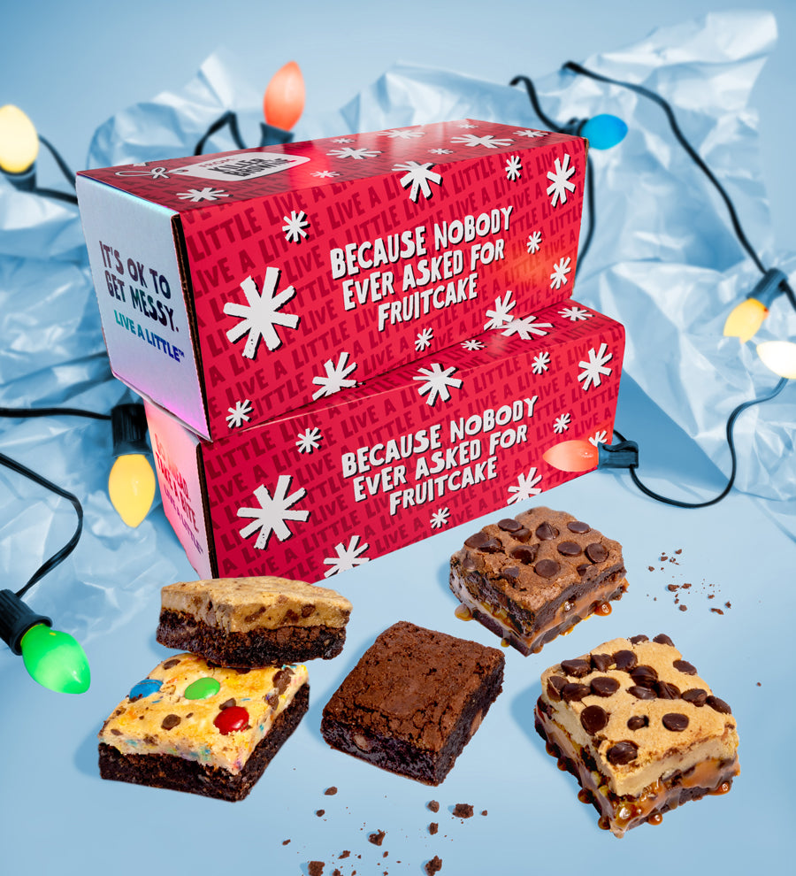 Red gift box with festive text and assorted brownies on a blue background with Christmas lights.