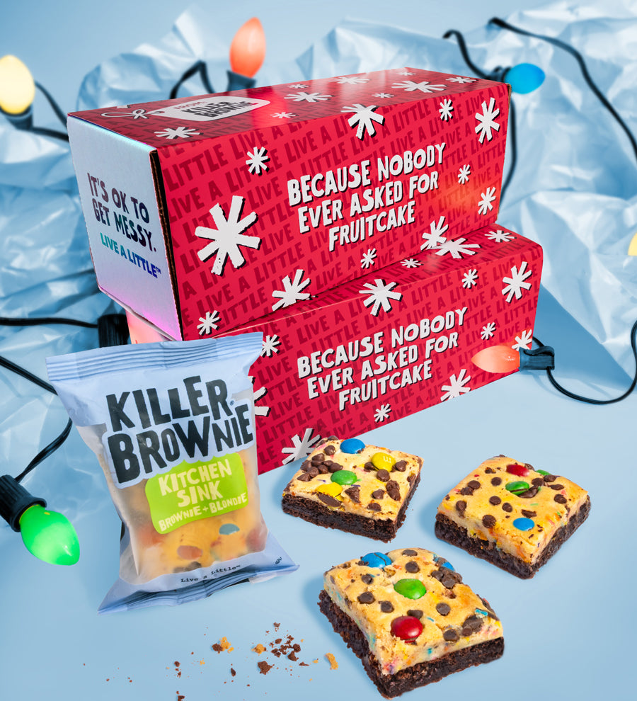 Red gift box with festive text, brownies, and a bag labeled 'Killer Brownie Kitchen Sink' on a light blue background.